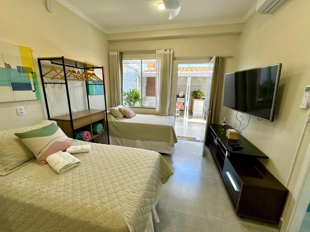 a bedroom with two beds and a flat screen tv at Studio Bena 2 - single bed - próx Shopping Iguatemi in Campinas