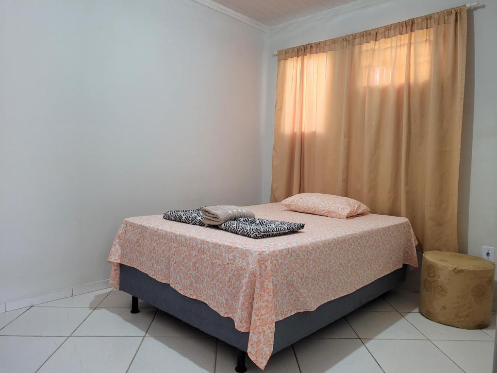 a bedroom with a bed with a pink blanket and a window at Lugarzin2 - Casa Privada - Garagem Compartilhada in Vitória da Conquista