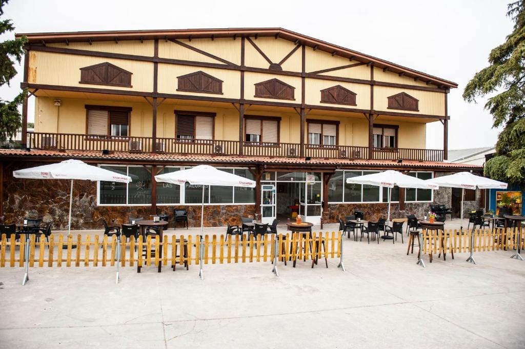 a building with tables and chairs and umbrellas at HOSTAL LAS PALOMAS in Lucena