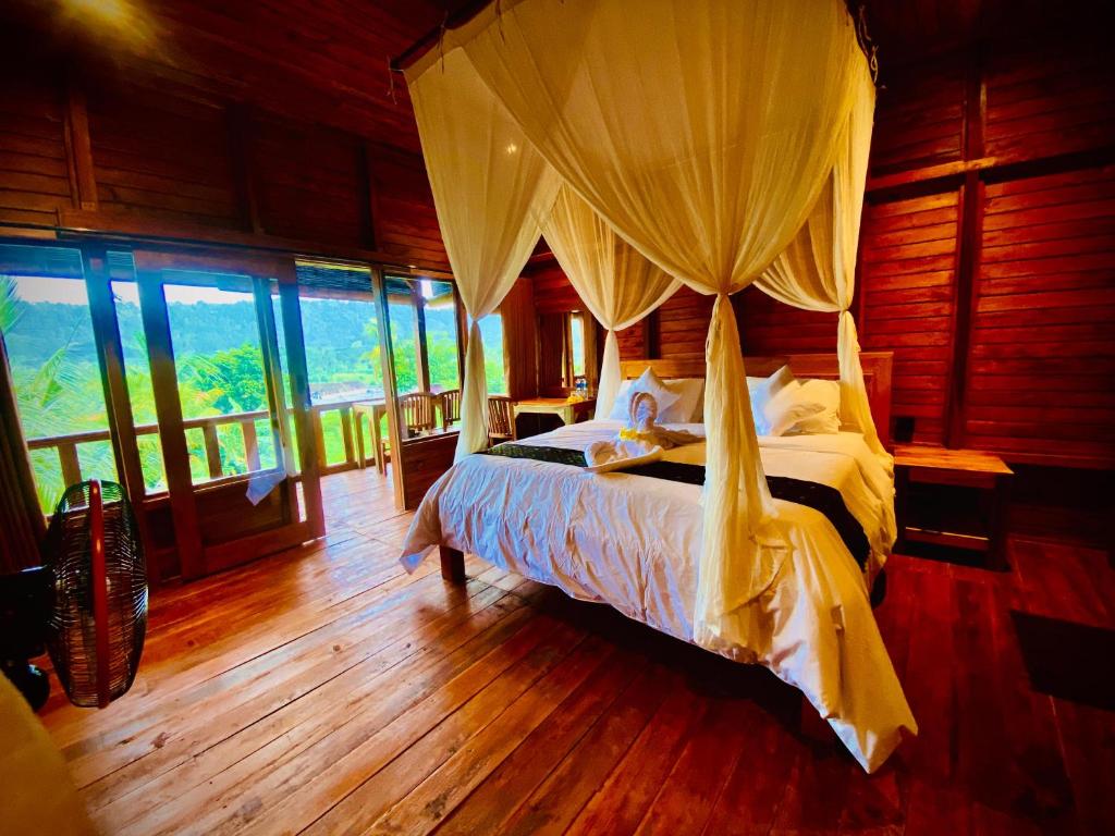1 dormitorio con 1 cama en una habitación con ventanas en Manuk Dewata Villa, en Sidemen