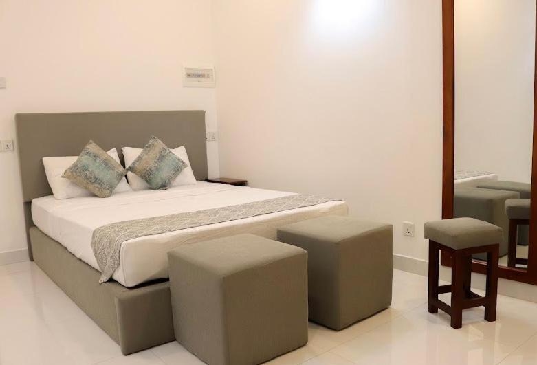 1 dormitorio con 1 cama grande y 2 taburetes en Rose Villa Accommodation, en Seeduwa
