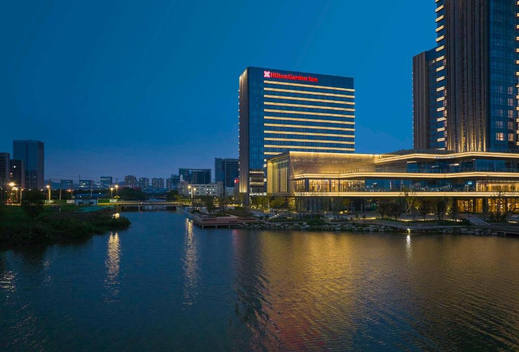 a large building next to a river in a city at Hilton Garden Inn Suzhou Wuzhong in Suzhou