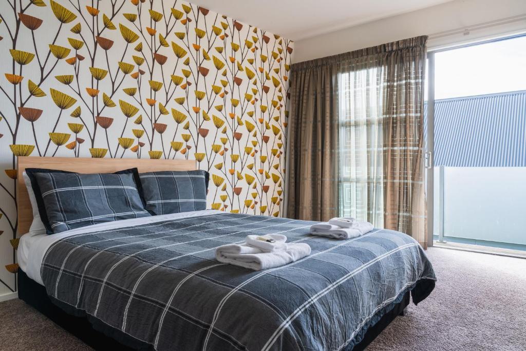 1 dormitorio con 1 cama con toallas en Urban Sanctuary on Union en Dunedin