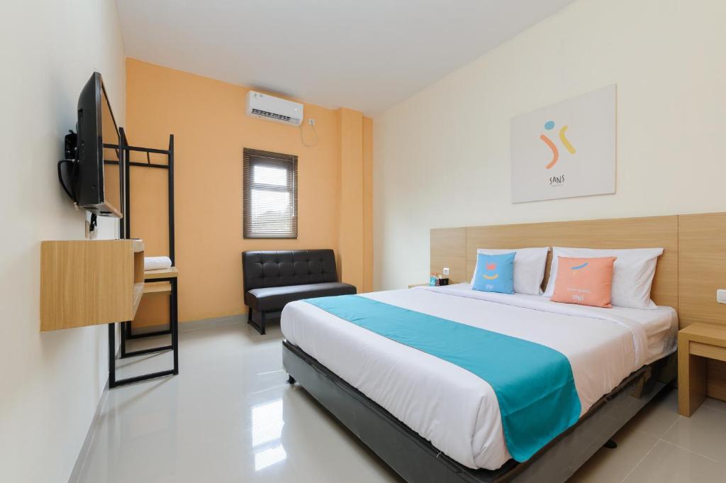 a bedroom with a bed and a desk and a television at Sans Hotel Cibanteng Dramaga Bogor in Bogor