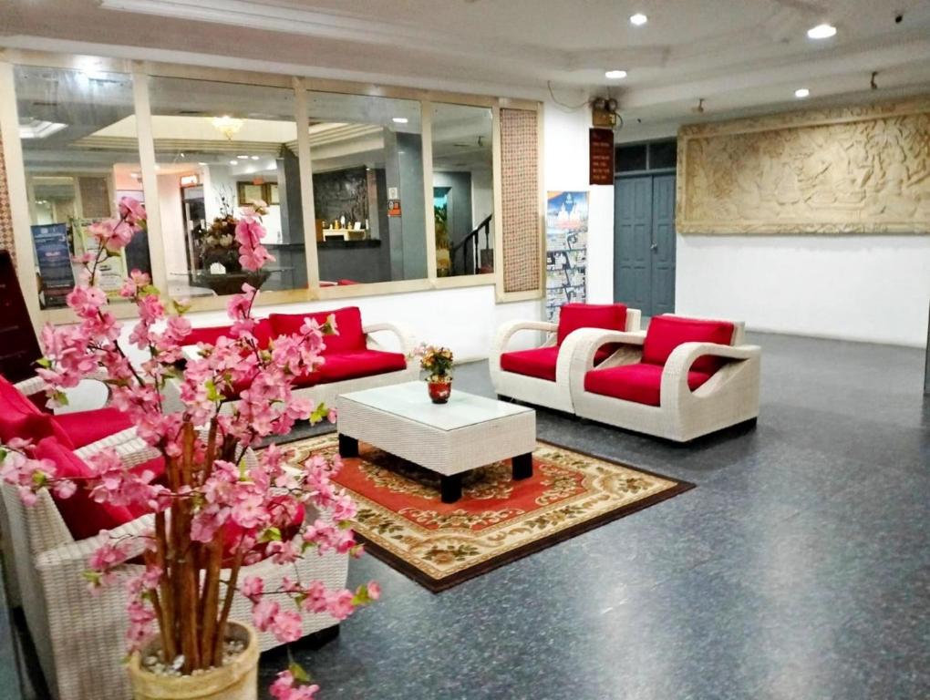 um átrio com mobiliário vermelho e branco e flores cor-de-rosa em Hotel Wisata Indah Sibolga em Sibolga