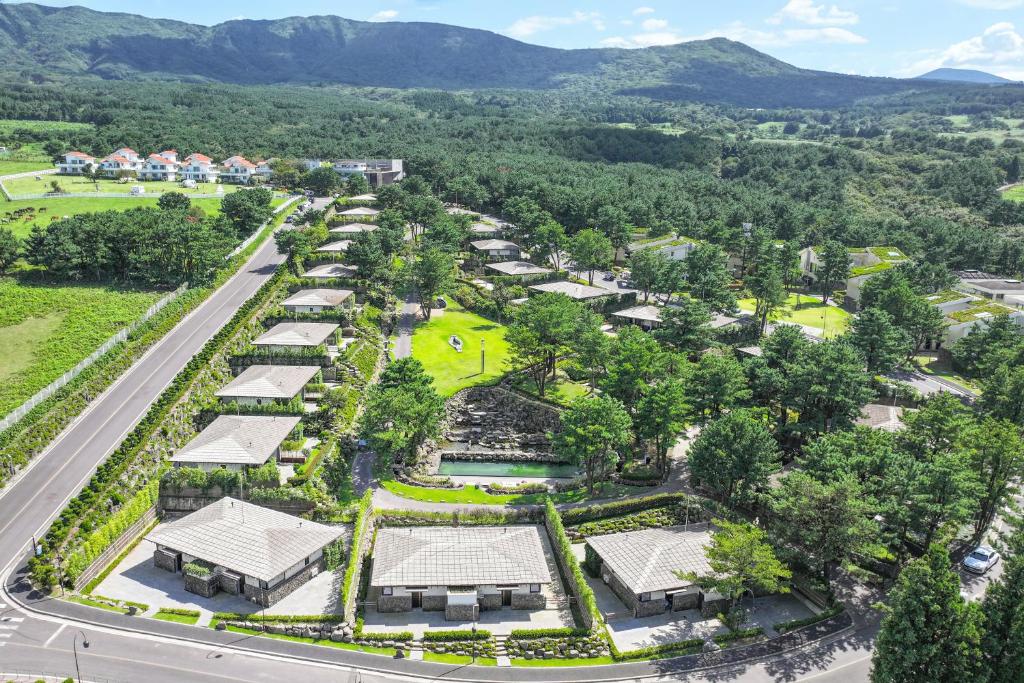 une vue aérienne sur un parc arboré et une route dans l'établissement Amber Pure Hill Hotels & Resorts Jeju, à Jeju