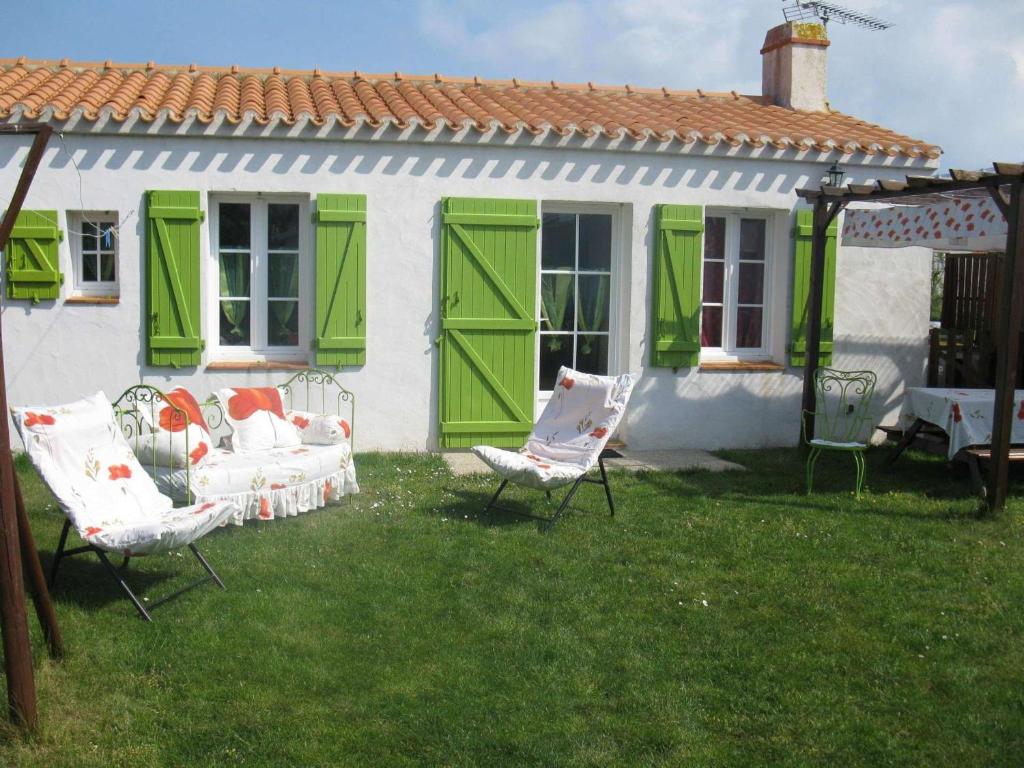 une cour avec des chaises et une maison avec des portes vertes dans l'établissement Maison Noirmoutier-en-l'Île, 2 pièces, 4 personnes - FR-1-224B-214, à Noirmoutier-en-l'lle