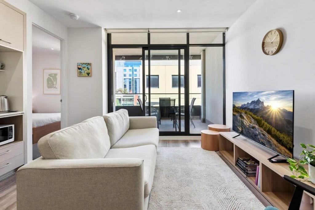 a living room with a white couch and a tv at Tasteful 2-Bed Unit By Bridge Rd Shops in Melbourne