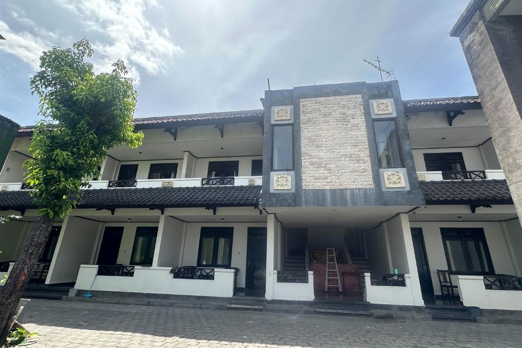 a large white building with a tree in front of it at HOTEL WARTA SARI in Denpasar