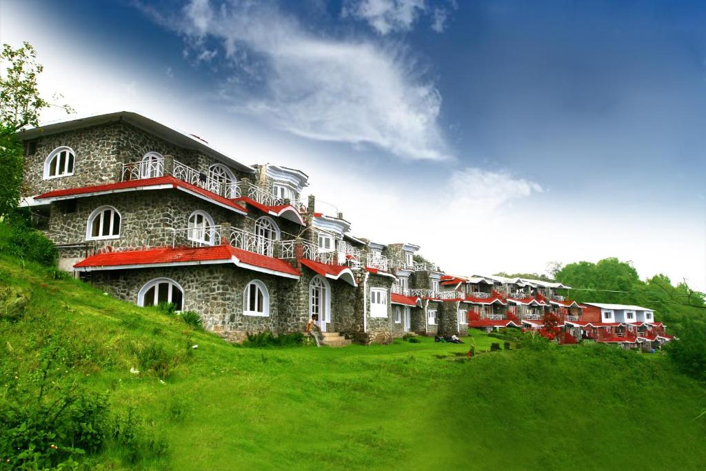 a large building on top of a green hill at The place The experience kodai in Kodaikānāl