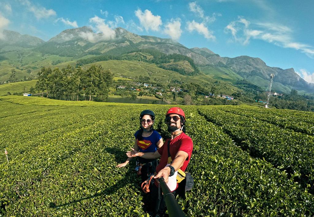 a man and a woman standing in a tea plantation at Campper Campwoody Munnar in Munnar