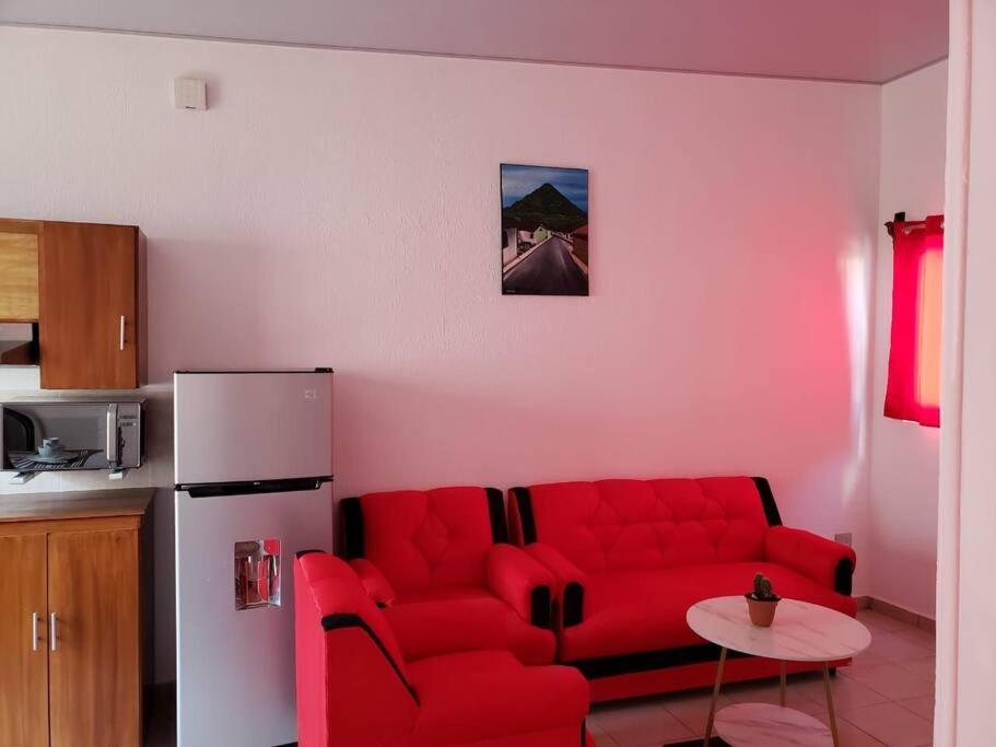 sala de estar con sofá rojo y nevera en Figueroa's House., en Santa Ana