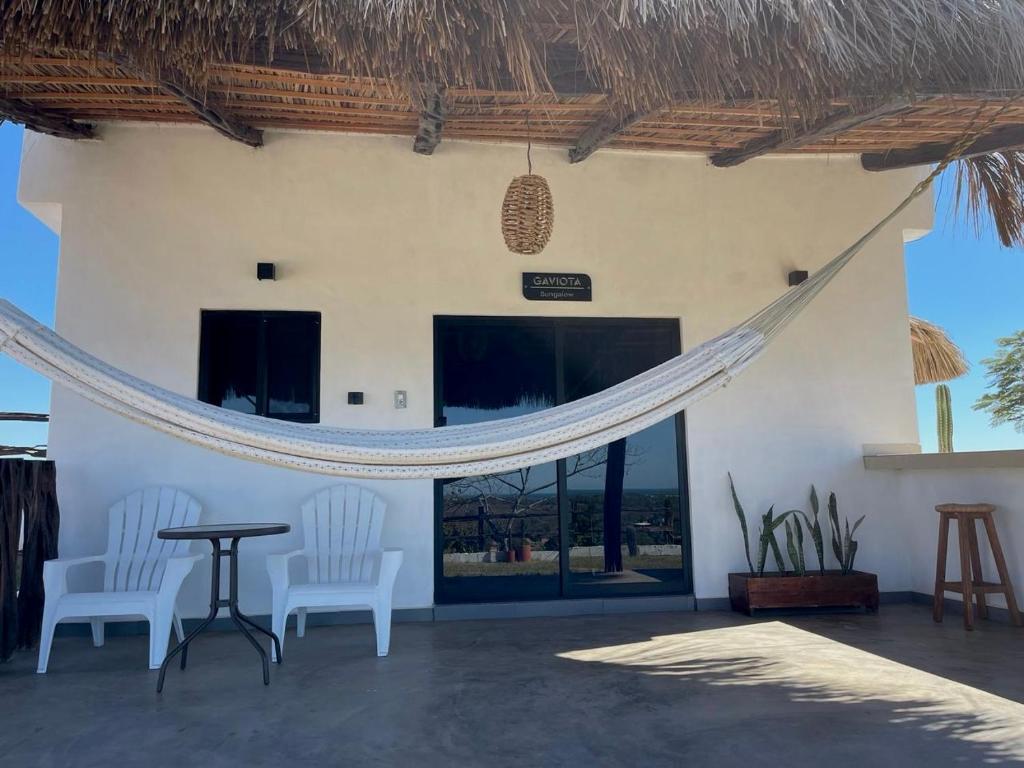 un patio con mesa y 2 sillas y un edificio en Bungalow Gaviota c/vistas increíbles al Océano Pacífico, en Perihuete