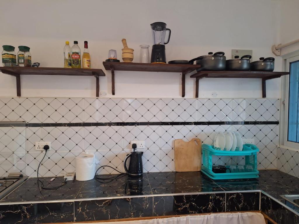 eine Küche mit schwarzen Arbeitsplatten und Regalen an der Wand in der Unterkunft Cool breeze in Ukunda