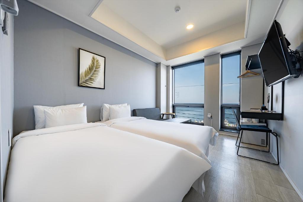 una camera d'albergo con due letti e una televisione di Stay Hostel a Sokcho