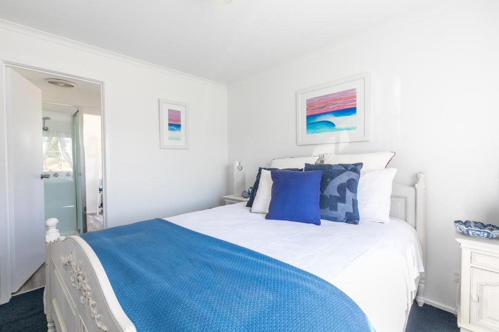 Un dormitorio con una cama blanca con almohadas azules. en Beach Paradise Family Friendly Close to Beach, en Ocean Grove