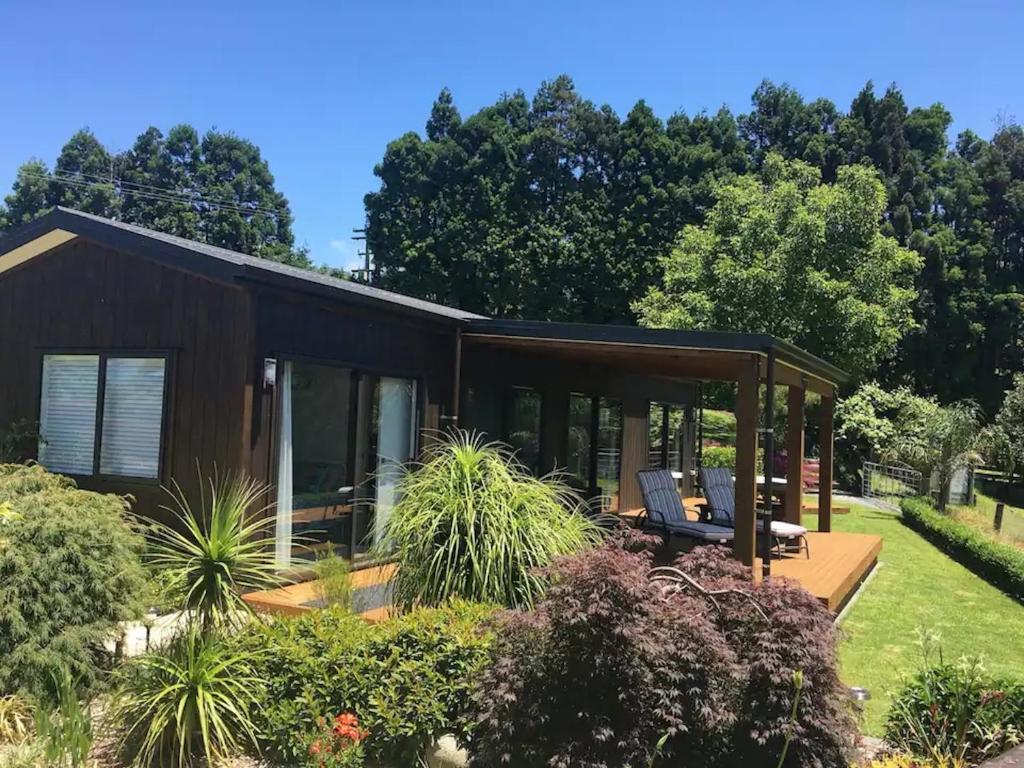 a small house with a large deck and windows at Kaimai Range Country Getaway in Katikati