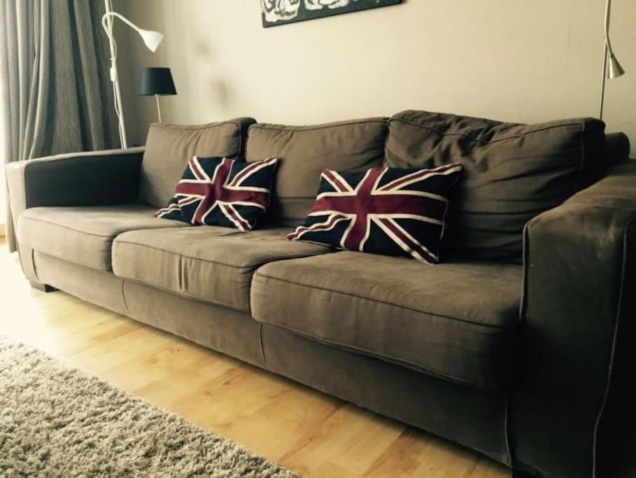 eine braune Couch mit zwei britischen Kissen drauf in der Unterkunft Appartement cosy au cœur du Zoute près de la plage in Knokke-Heist