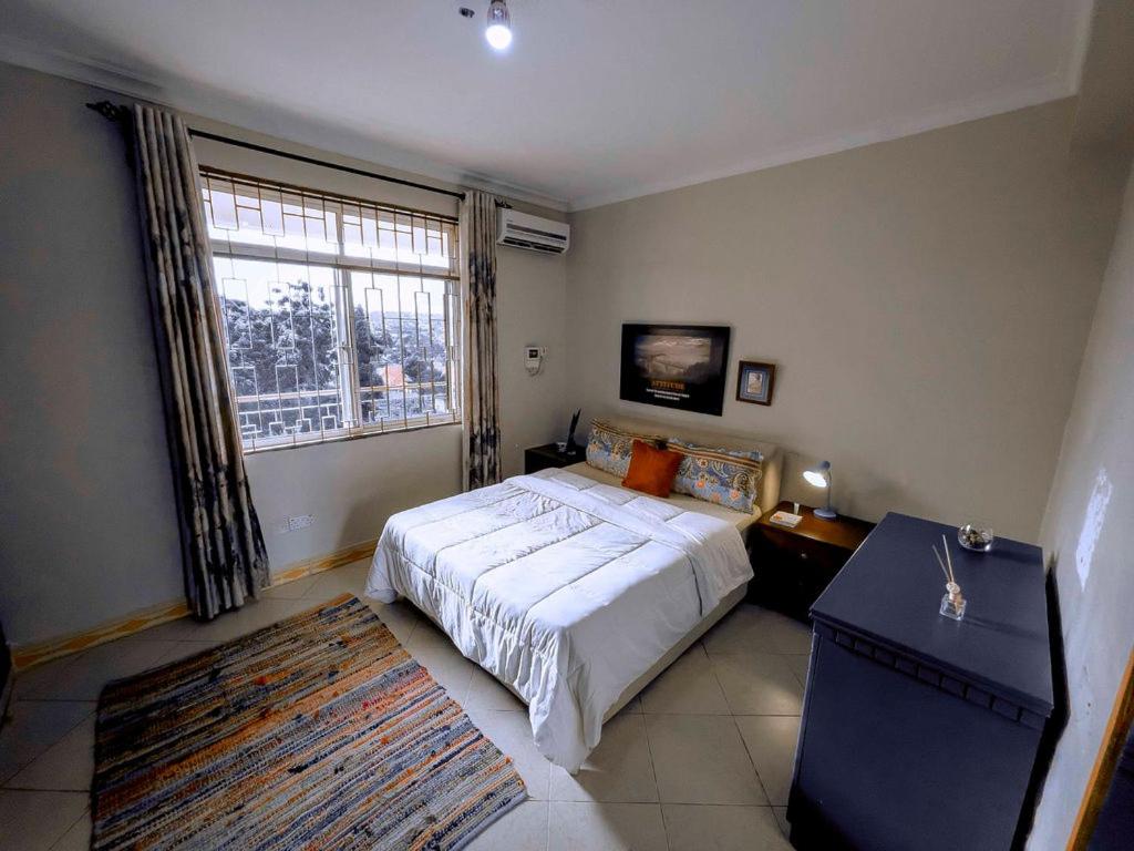 a bedroom with a bed and a large window at Olive Escapes in Dar es Salaam