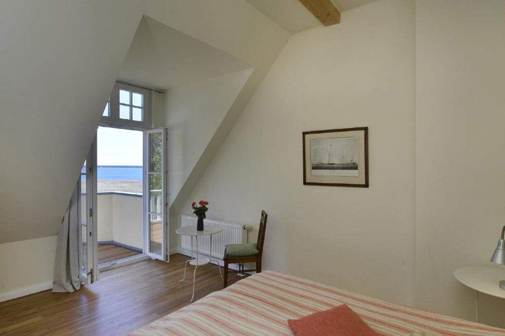 a bedroom with a bed and a table and a window at Gut Grubnow Rügen - Ferienwohnung 6 in Neuenkirchen