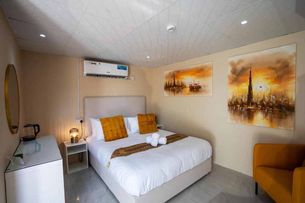 1 dormitorio con 1 cama blanca grande con almohadas de color naranja en Desert Safari Overnight Experience "Modern room with AC & Entertainment", en Hunaywah