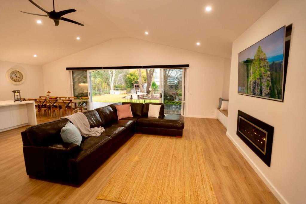 a living room with a leather couch and a fireplace at The Bonnie Ray in Porepunkah