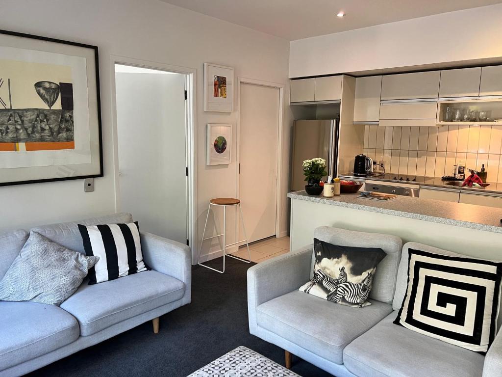a living room with two couches and a kitchen at Lovely 2 bedrm apartment in Auckland's viaduct in Auckland