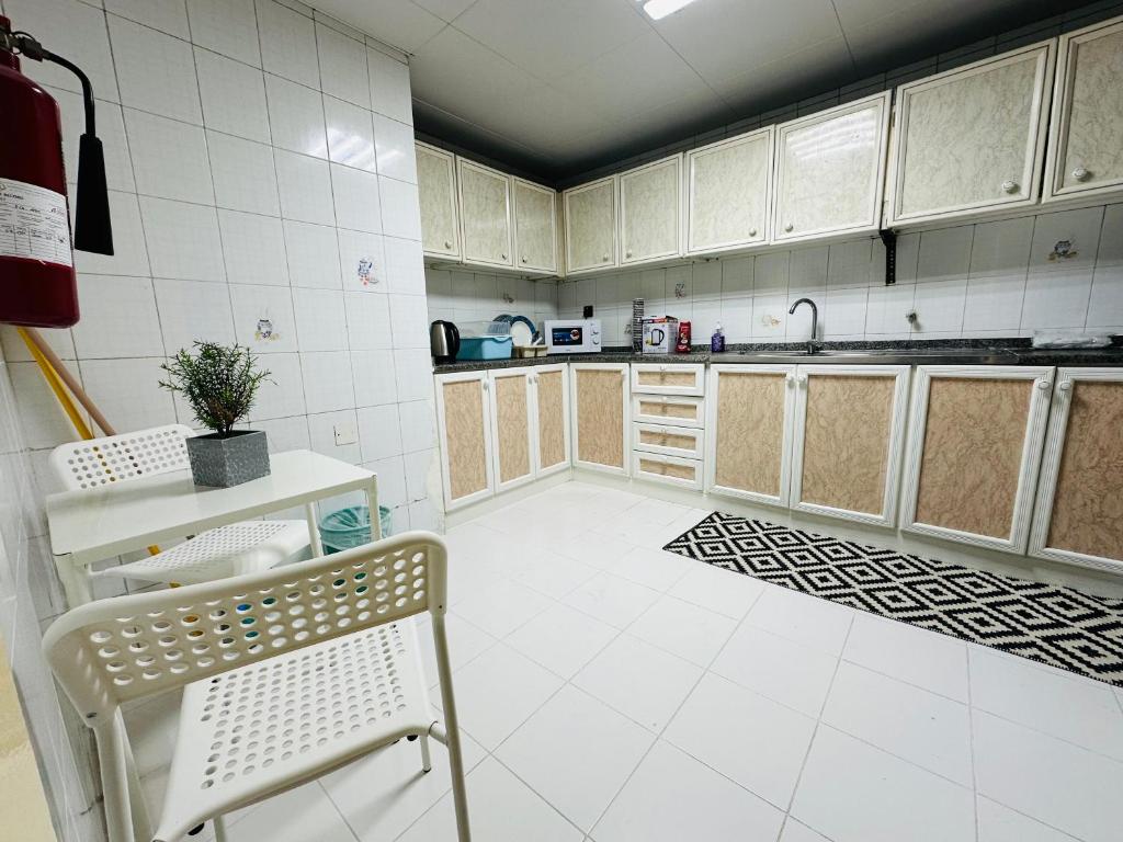 een keuken met witte kasten en een stoel. bij Sunrise Inn by DSV Property in Abu Dhabi