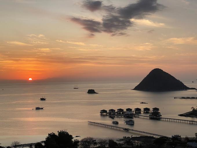 einen Sonnenuntergang über dem Meer mit Booten im Wasser in der Unterkunft Sunset Hill Hotel in Labuan Bajo