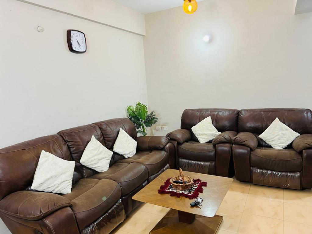 a living room with two brown leather couches and a coffee table at Royal Home Stay in Patna