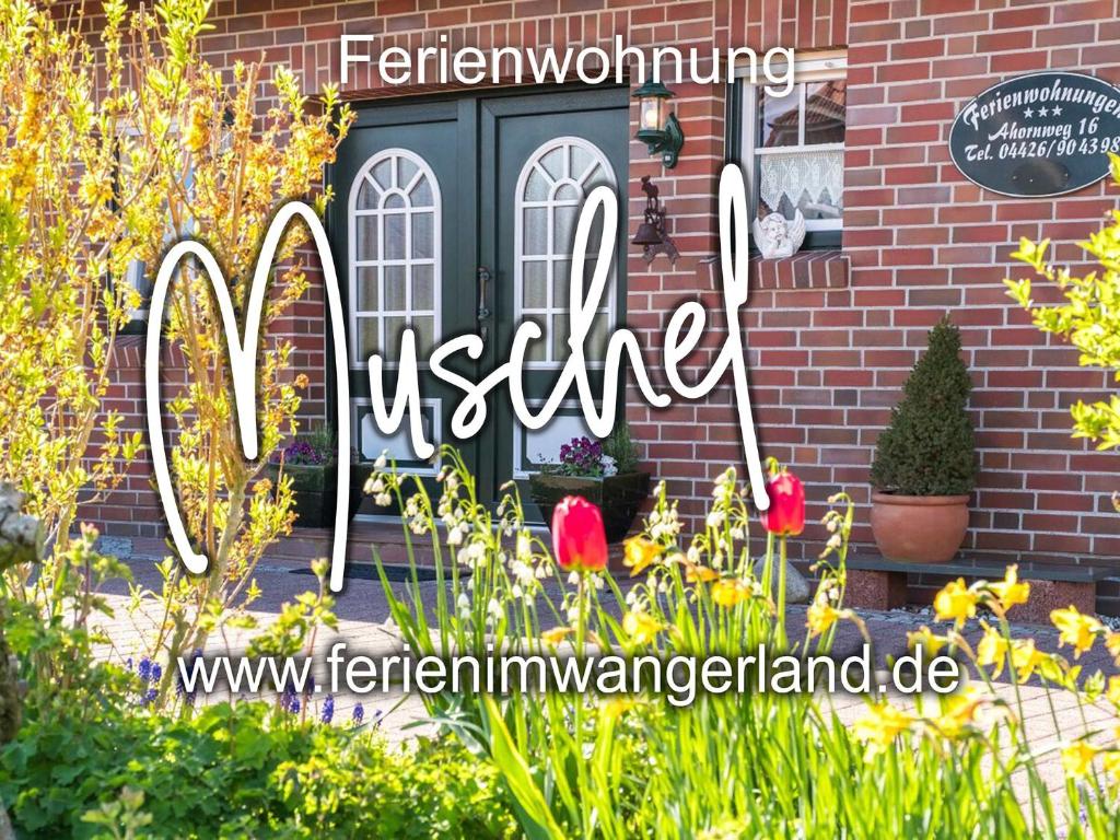 een bord voor een huis met bloemen bij Ferien im Wangerland Ferienwohnung MUSCHEL Minsen Schillig Hund Pool Sauna in Wangerland