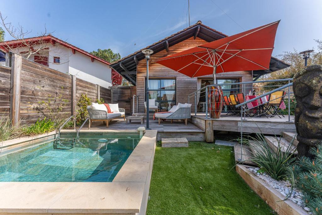 une maison avec une piscine et un parasol dans l'établissement Villa AMAYA, Pyla/ Le Moulleau, à La Teste-de-Buch