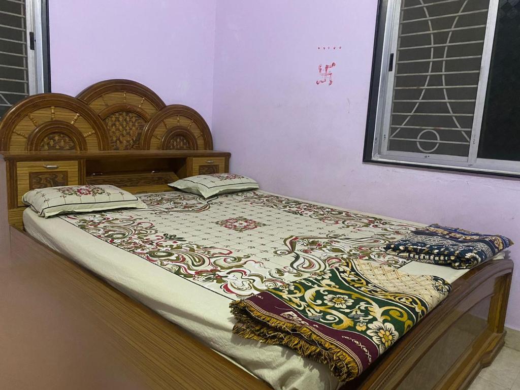 a bed with a wooden headboard and a blanket on it at Laxmi Kunj in Akalkot