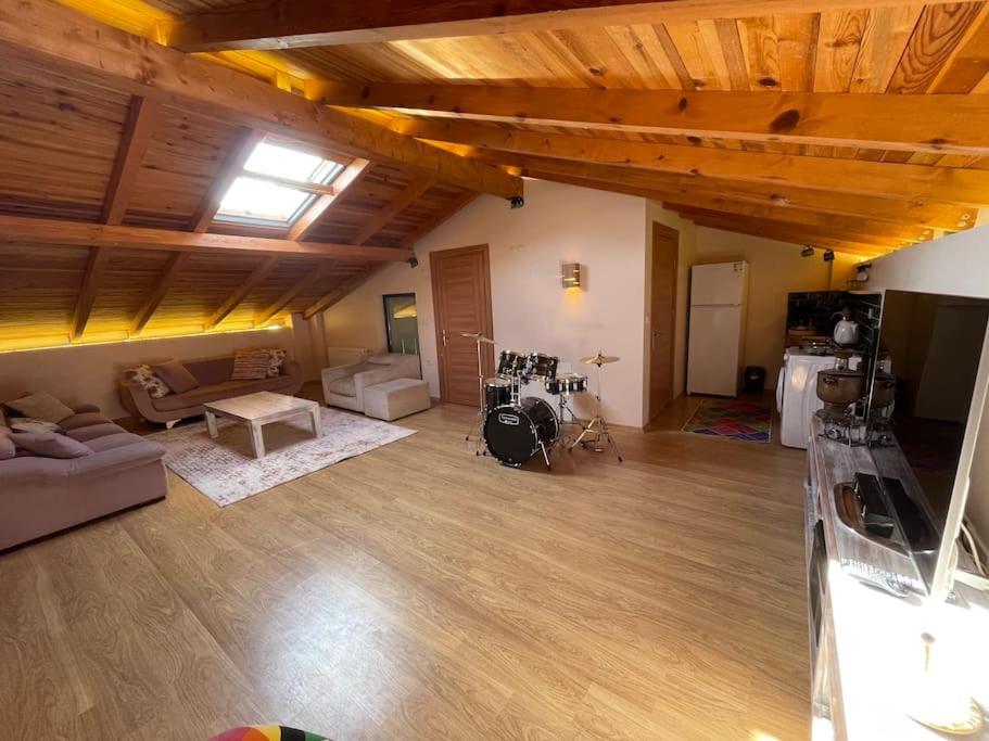 una gran sala de estar con techos de madera y una habitación con sofá. en Gökler Çiftliğinde Çatı Katı, en Foca