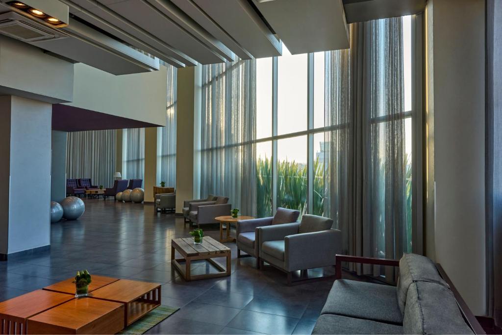 Floor-to-ceiling windows brighten a spacious lounge with sofas, armchairs, coffee tables, and exercise balls in the background.