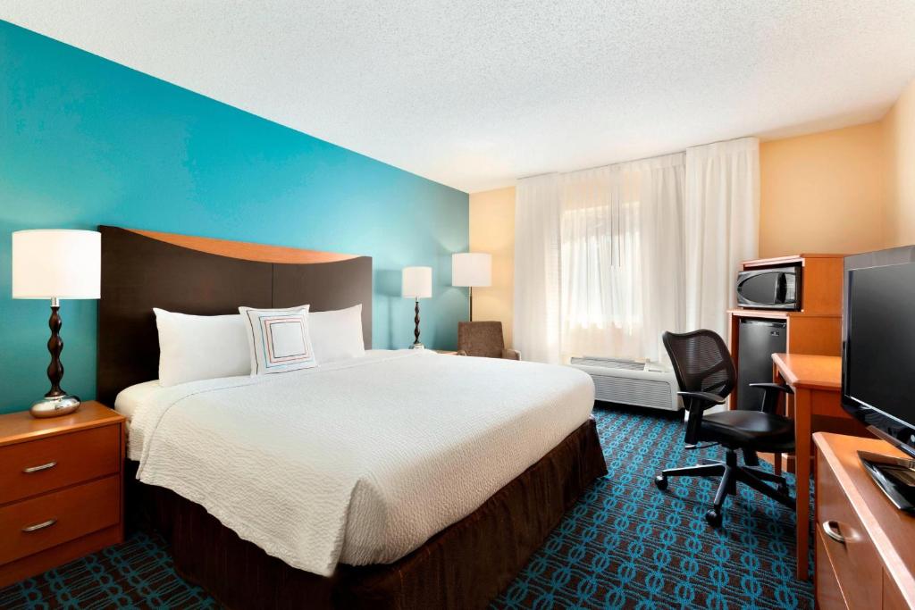 a hotel room with a bed and a flat screen tv at Fairfield Inn & Suites Midland in Midland