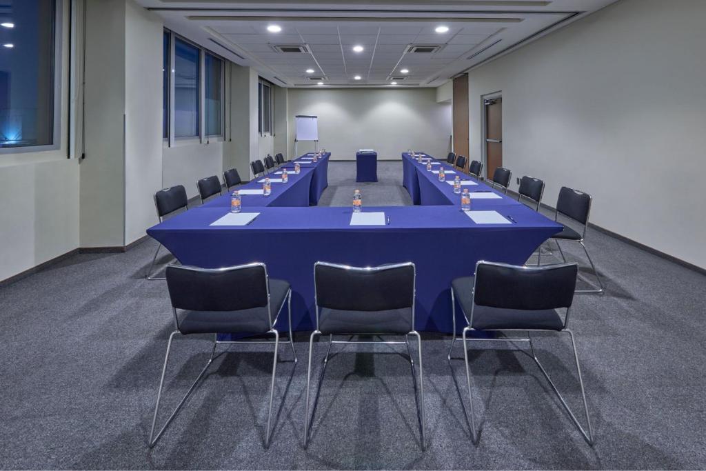 A long conference room arranged around a blue-clothed central table.