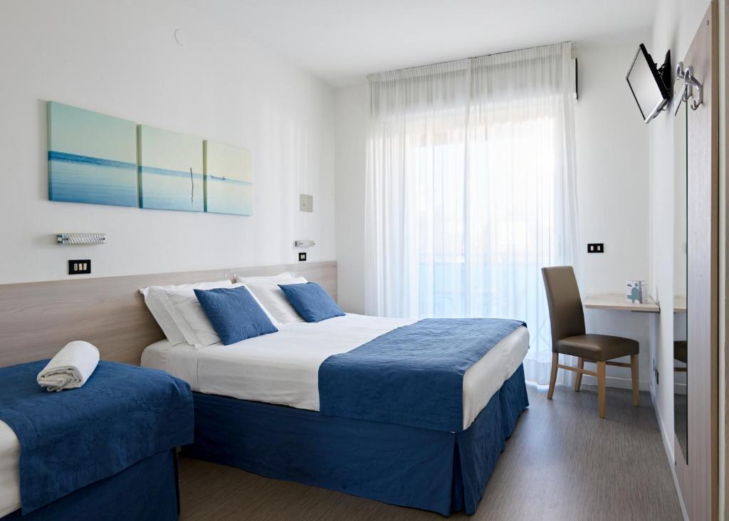 a hotel room with two beds and a table and a chair at Hotel Bahia in Lignano Sabbiadoro