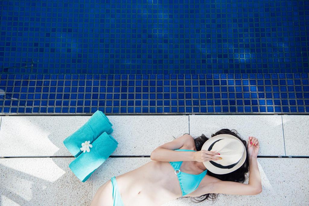 a woman laying on the ground next to a swimming pool at Hotel Palm Royal Naha Kokusai Street in Naha