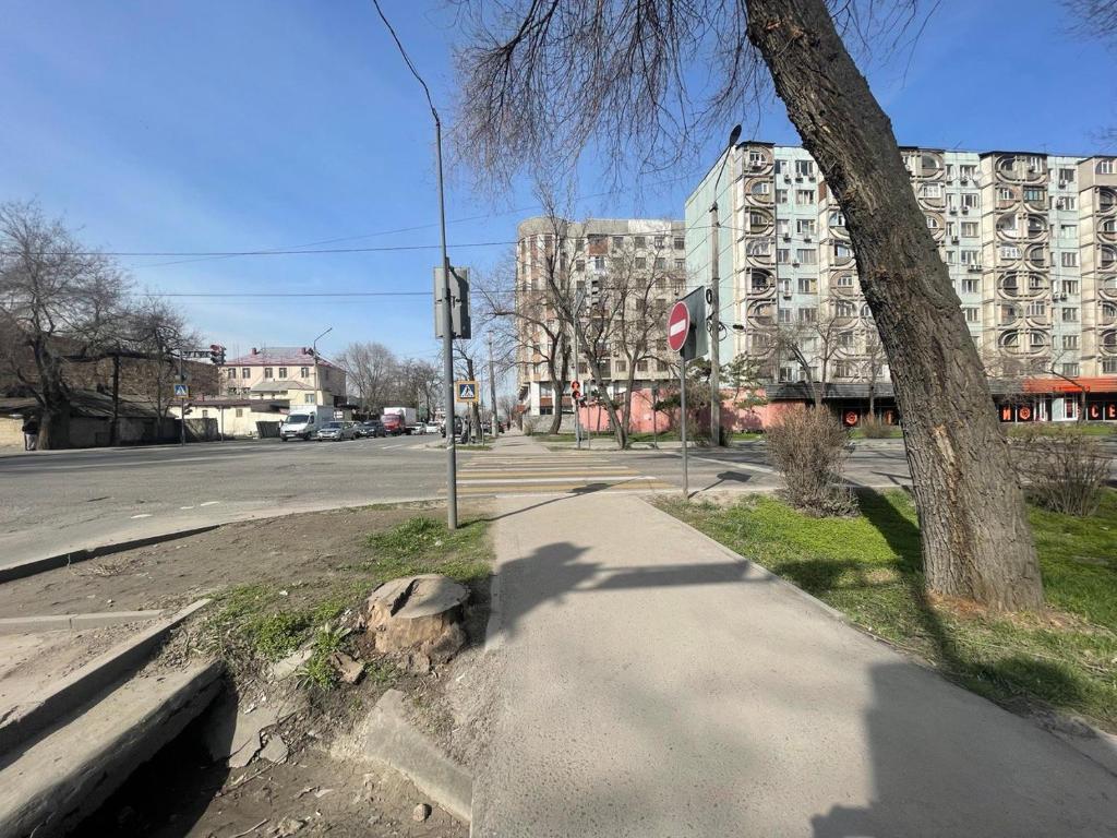 una calle vacía con un árbol y un edificio en Квартира в Бишкеке, en Bishkek
