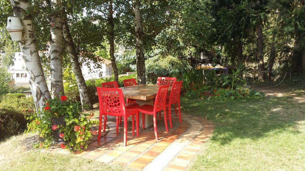 une table avec quatre chaises rouges dans un jardin dans l'établissement Appartement Chantemerle, à Durtol