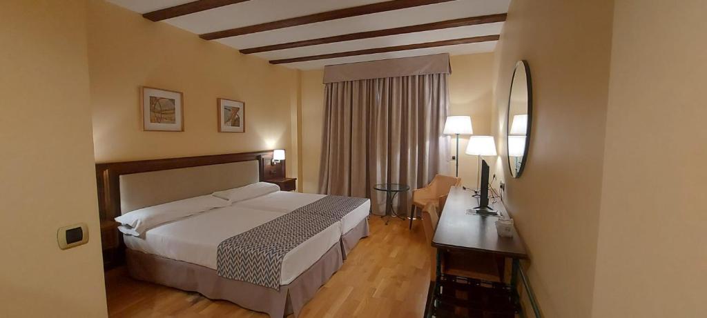 a hotel room with a bed and a desk at Hotel Spa Tudanca Aranda in Aranda de Duero