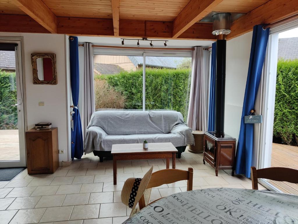 een woonkamer met een bed en een groot raam bij Maison calme et lumineuse de plain-pied in Cabourg