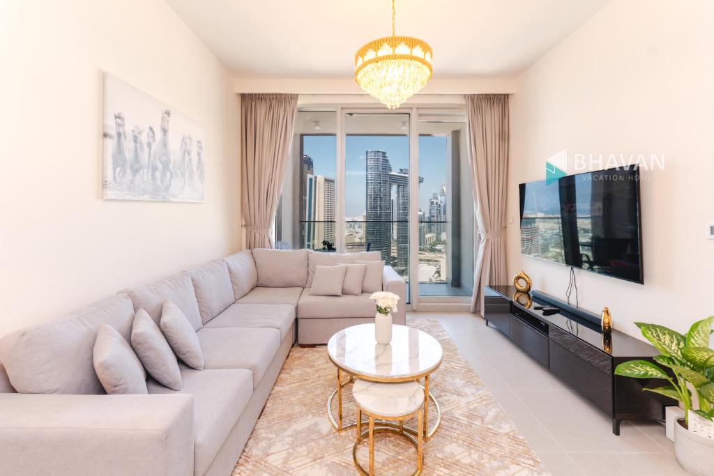 a living room with a large couch and a tv at Fabulous 2BR high floor luxury apartment with Burj Khalifa view in Dubai