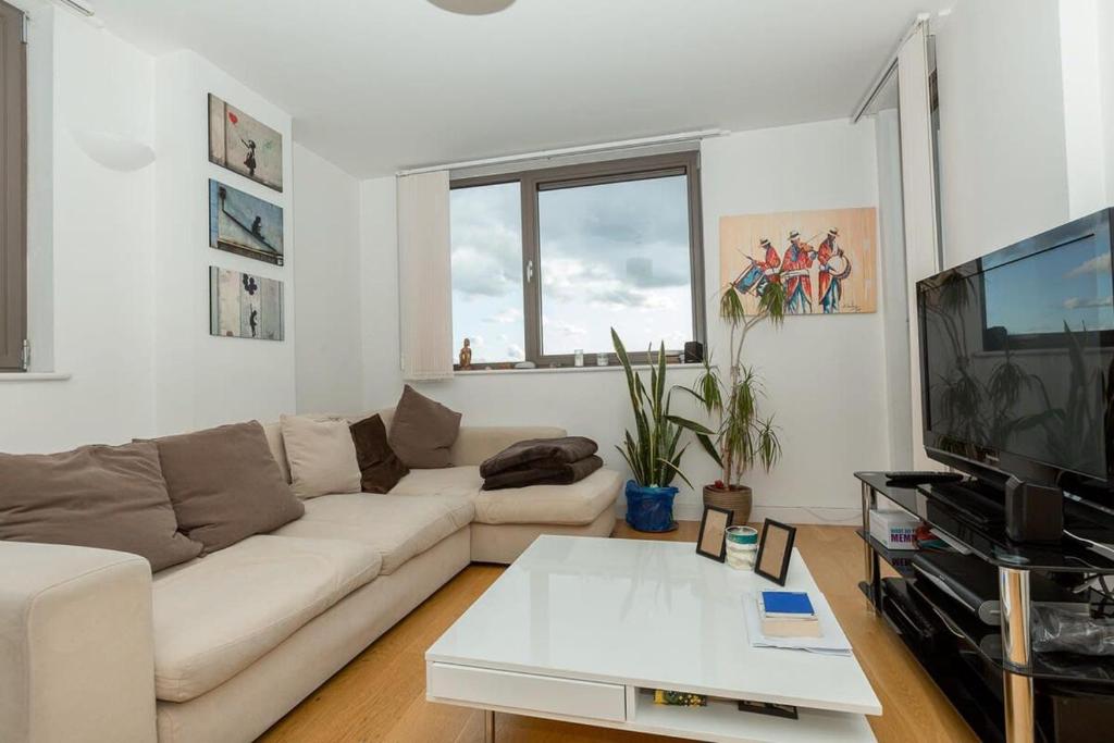 a living room with a white couch and a tv at 2 Bedroom East London Apartment With Amazing Views in London