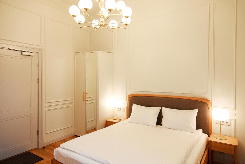 a bedroom with a white bed and a chandelier at Roze Center Apartments in Liepāja