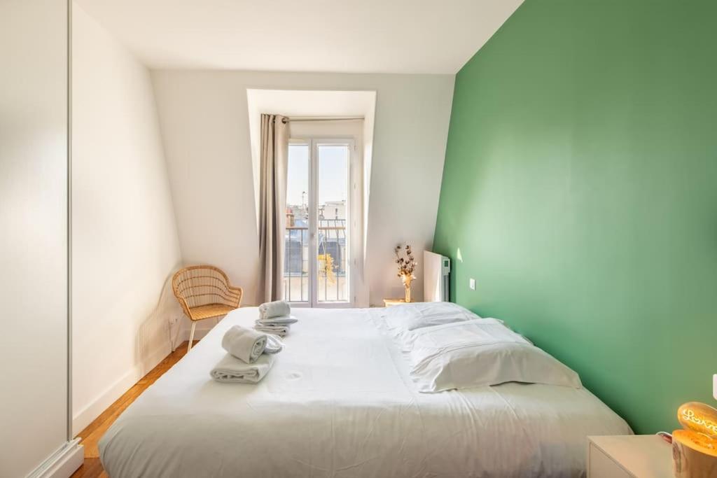 a large white bed in a room with a window at Secrétan - Charmant appartement au pied des Buttes Chaumont in Paris