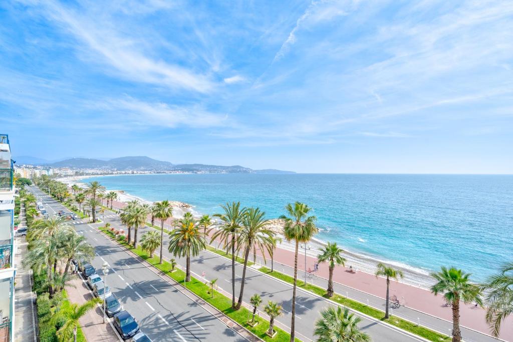 - une vue sur la plage et les palmiers dans l'établissement Magnifique 3P promenade des anglais, à Nice