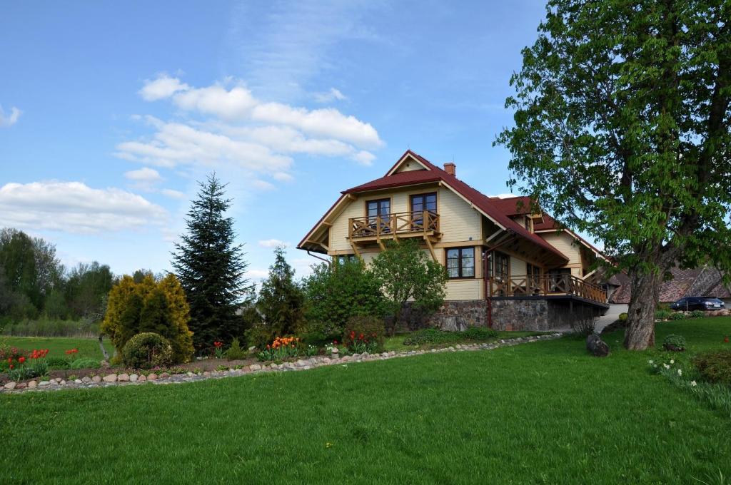 una casa grande con un césped verde delante de ella en Viesu nams Bezdubeņi, en Sukturi