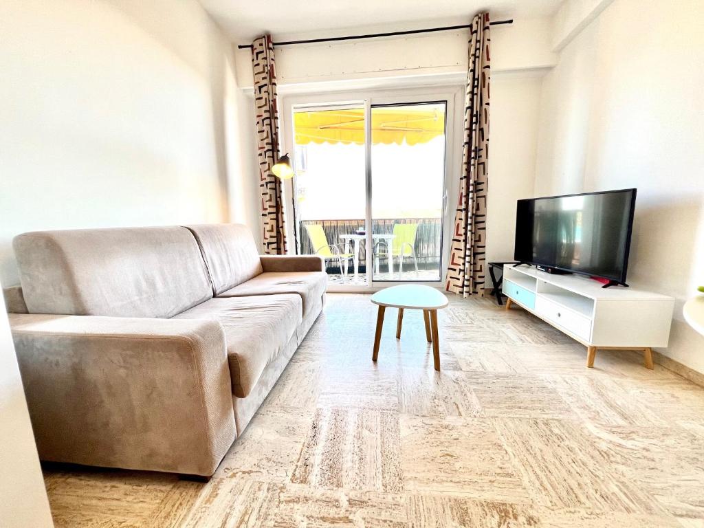 un salon avec un canapé et une télévision dans l'établissement ApartHotel Riviera - Terrasse des Bougainvillees - 100m Promenade des Anglais, à Nice